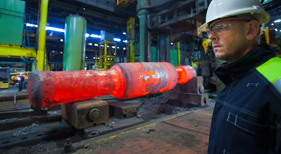Engineer beside glowing hot steel in a mill