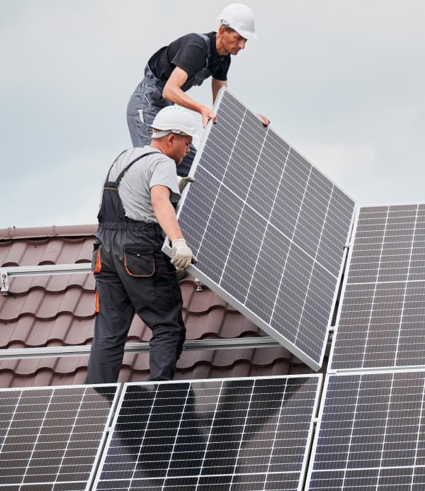 Installers placing solar panels on a roof